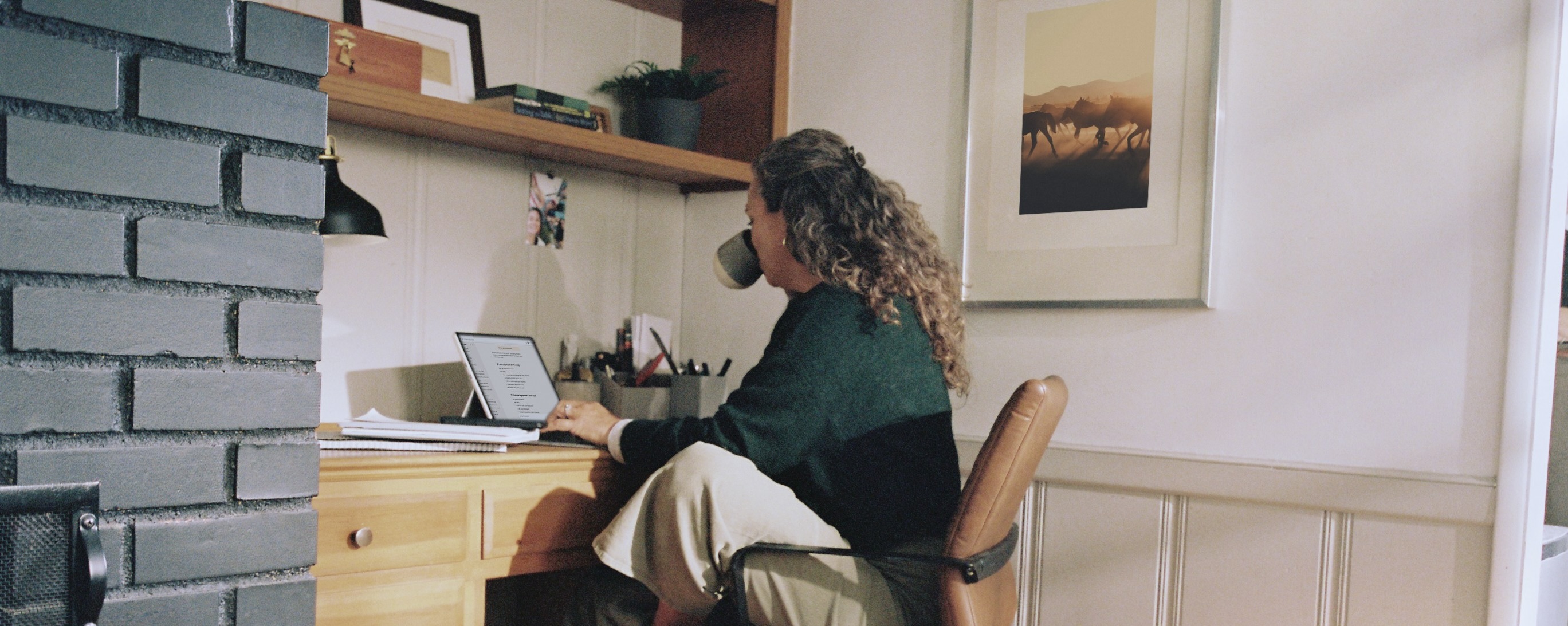 Professional working at a home office desk with a tablet and warm natural light