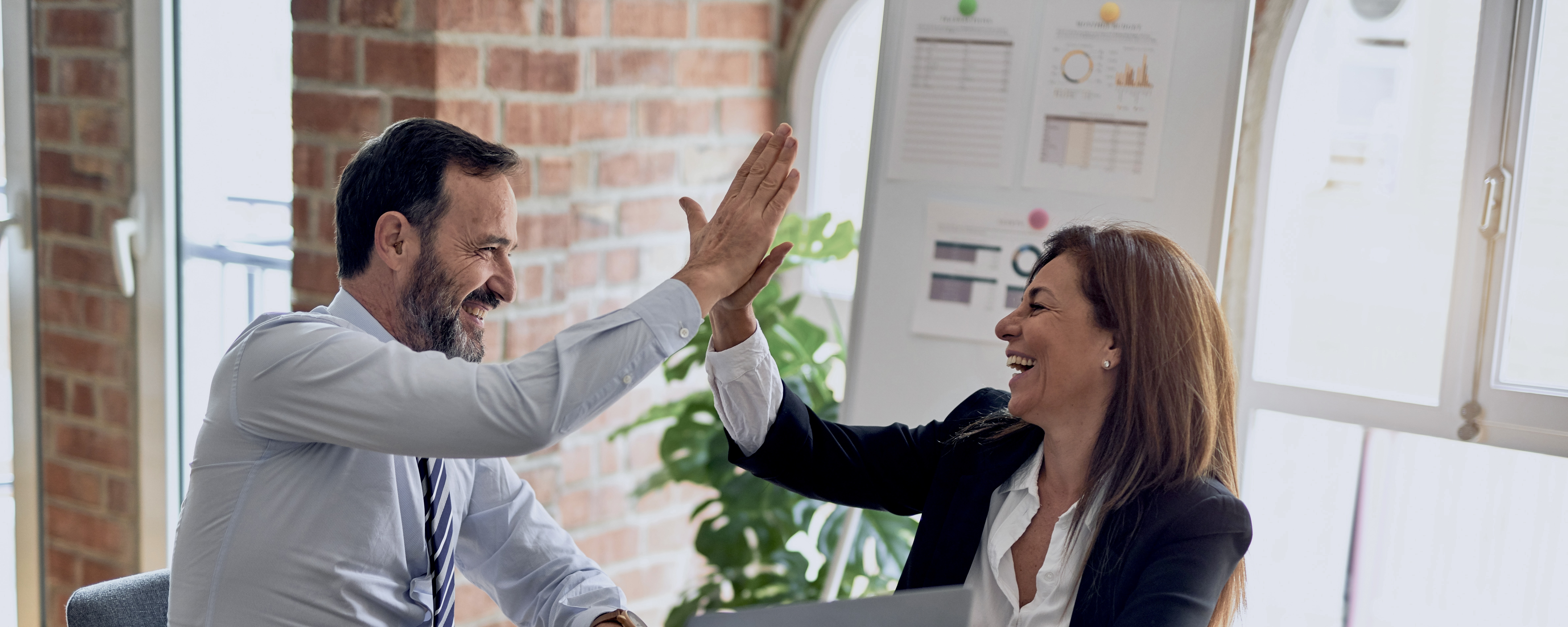 Business colleagues celebrating a successful outcome with a high five in a modern office